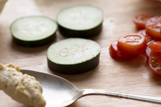 Getting ready to make healthy cucumber and hummus snacks topped with tomatoes.