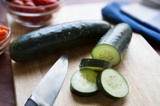 Cucumbers and knife on cutting board.