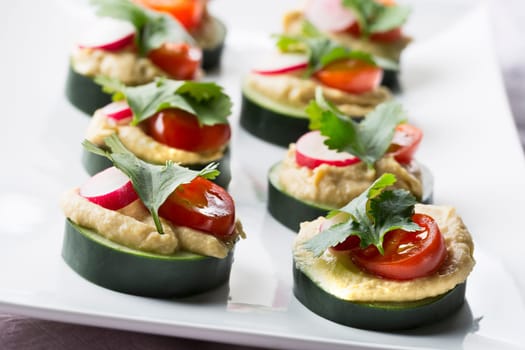 Healthy cucumber hummus bites with tomato, radish and cilantro.