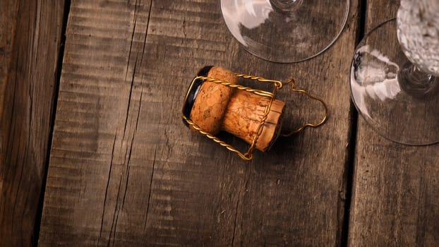 Cork of a champagne bottle against two champagne flutes