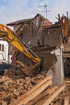 A large track hoe excavator tearing down an old house