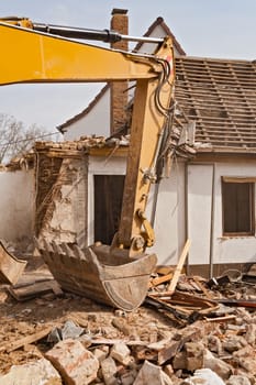 A large track hoe excavator tearing down an old house