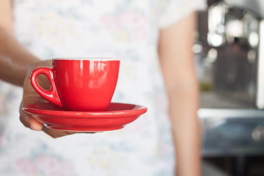 Woman's hand holding red coffee cup, stock photo