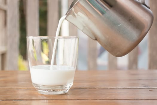 Pour milk from a pitcher into a glass, stock photo