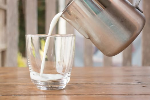 Pour milk from a pitcher into a glass, stock photo