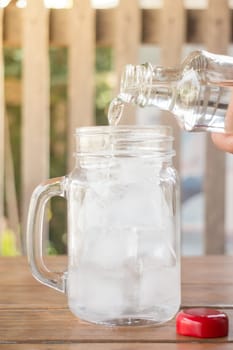 Drinking water is poured into iced glass, stock photo