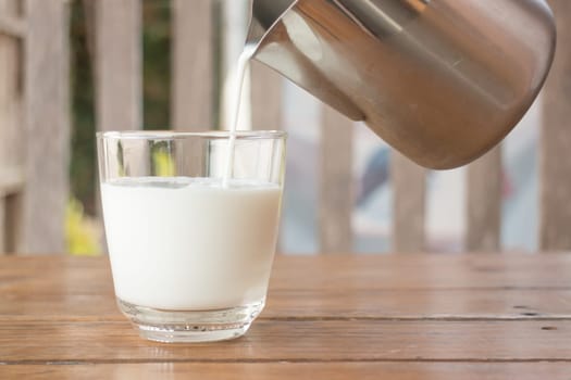 Pour milk from a pitcher into a glass, stock photo