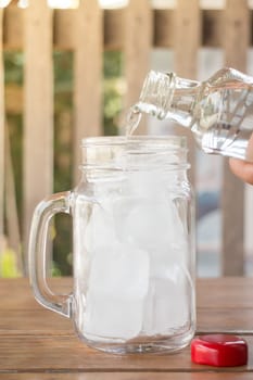 Drinking water is poured into iced glass, stock photo