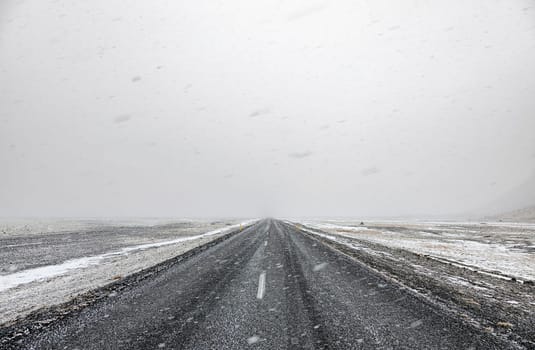 Snow falling on a country road in iceland in the winter