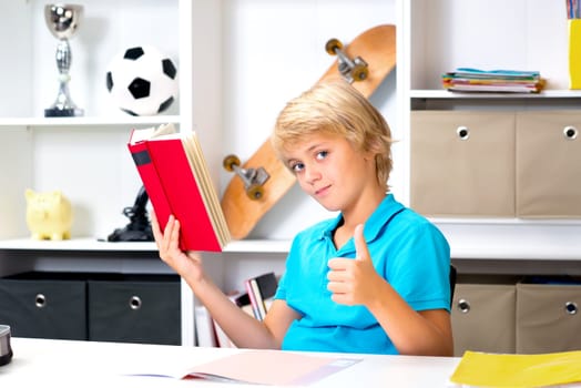 blond boy with thumb up reading a book