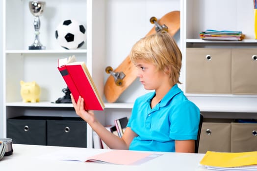 blond boy doing homework and reading a book