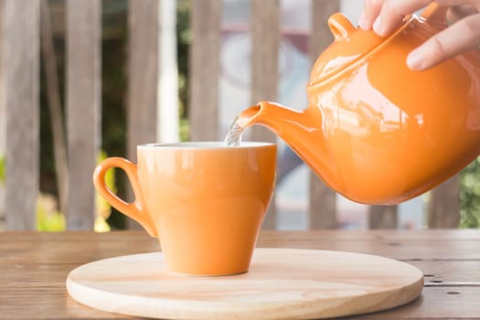 Hot tea is poured from teapot into a cup, stock photo