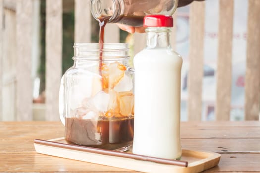 Pouring espresso to iced glass of coffee, stock photo