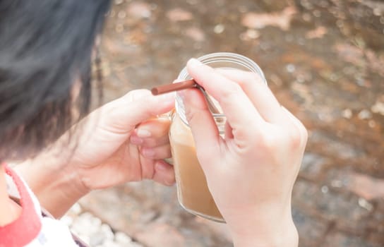 Hand on glass of iced milk coffee with vintage filter effect, stock photo