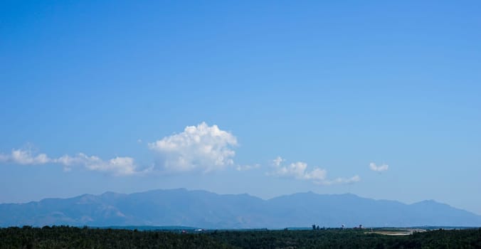 breathtaking panoramic landscape beyond tropical forest towards the mountains and the beautiful blue sky