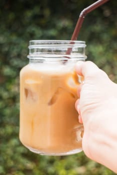 Hand on glass of iced milk coffee with vintage filter effect, stock photo