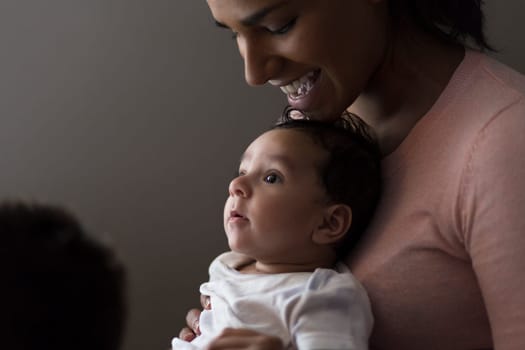 Young mother enjoying a cuddle with her baby son, who is sitting on her lap.