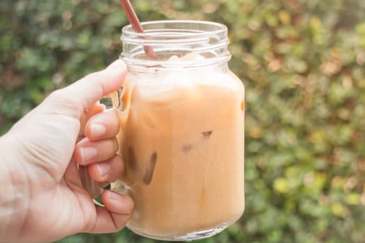 Hand on glass of iced milk coffee with vintage filter effect, stock photo