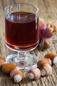 Homemade Hazelnut liqueur in a glass and hazelnuts of an old rustic wooden table