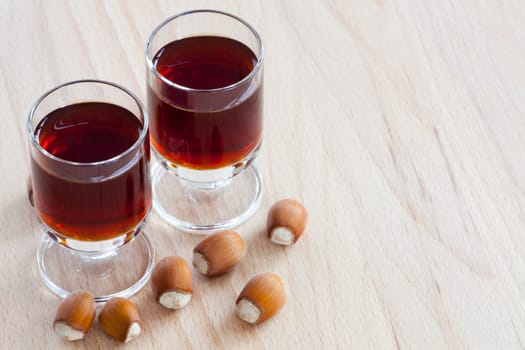 Two glasses with homemade hazelnut liqueur on wooden background
