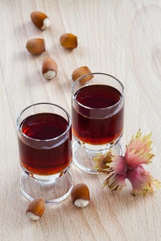 Homemade Hazelnut liqueur in two glasses and hazelnuts on wooden background