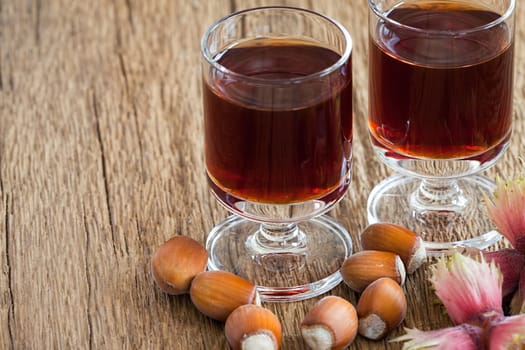 Homemade Hazelnut liqueur in two glasses and hazelnuts of an old rustic wooden table