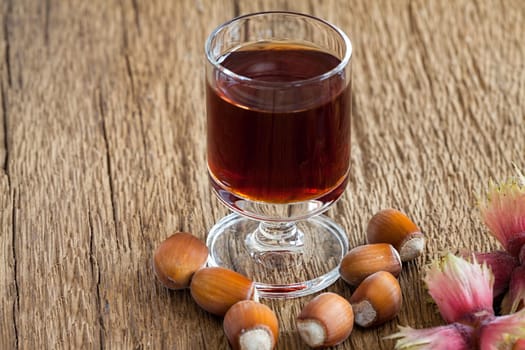 Homemade Hazelnut liqueur in a glass and hazelnuts of an old rustic wooden table