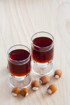 Two glasses with homemade hazelnut liqueur on wooden background
