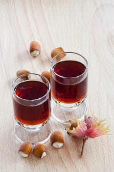 Homemade Hazelnut liqueur in two glasses and hazelnuts on wooden background