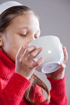 Little girl with her mugful (or cup) drinking her milk