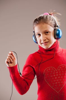 Little girl listening to the music inher blue headphones