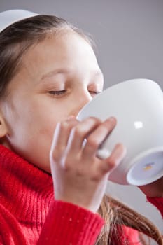 Little girl with her mugful (or cup) drinking her milk