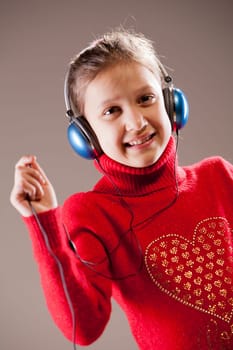 Little girl listening to the music inher blue headphones
