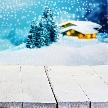 Winter or Christmas advertising background with empty white painted rustic wooden boards overlooking a lighted snowy timber mountain cabin with falling snow for product placement