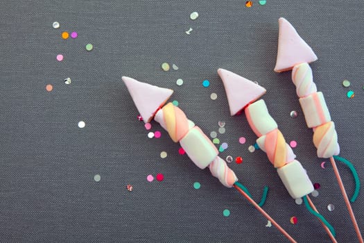 Conceptual Sweet Marshmallow Forming Rocket Fireworks on Gray Cloth Background with Attractive Colored Sequence.