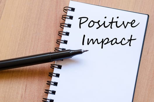 Positive impact text concept write on notebook with pen