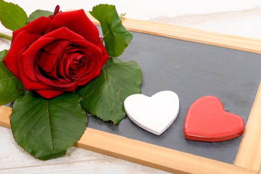 a red rose and black slate on a wood background