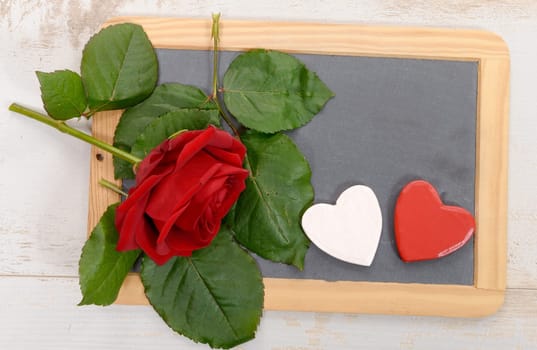 a red rose and black slate on a wood background