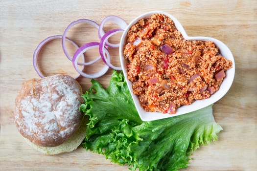 Heart healthy vegan sloppy joe sauce made with quinoa, with a bun, lettuce and onion.