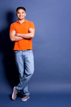 young casual man wearing orange tshirt on blue background