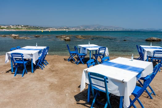 Tables with chairs in traditional Greek tavern in Kolympia town on coast of Rhodes island, Greece.