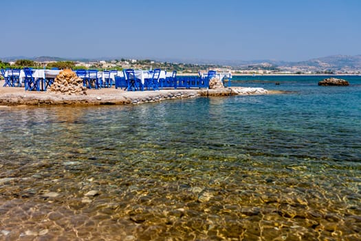 Tables with chairs in traditional Greek tavern in Kolympia town on coast of Rhodes island, Greece.