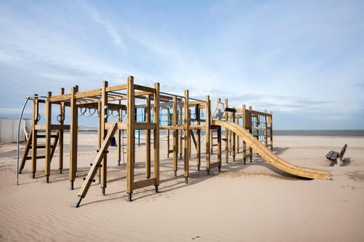 Wooden playground on the beach and a bench