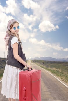 young girl on road with vintage clothes and suitcase