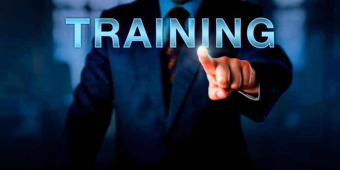 Corporate human resources manager is pressing TRAINING on a touch screen interface. Business concept for continued professional development, life-long learning and improvement of performance.