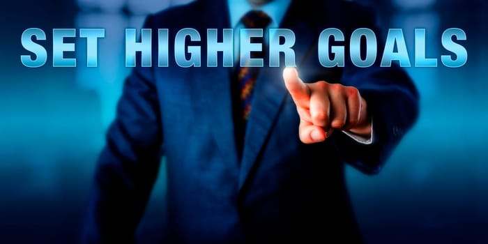Corporate career coach is touching SET HIGHER GOALS onscreen. Business concept for envisioning personal and organizational results towards one is committing to aspire within a limited timeframe.