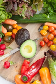 Fresh vegetables for a salad around rustic wood cutting board