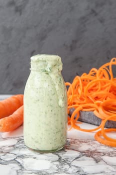 Bottle of yoghurt dressing with fresh salad of carrots