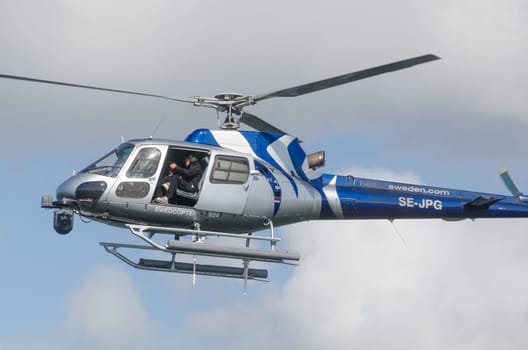 one blue and silver helicopter in the sky and take some picture with the camera