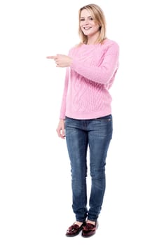 Young woman pointing index finger at copy space